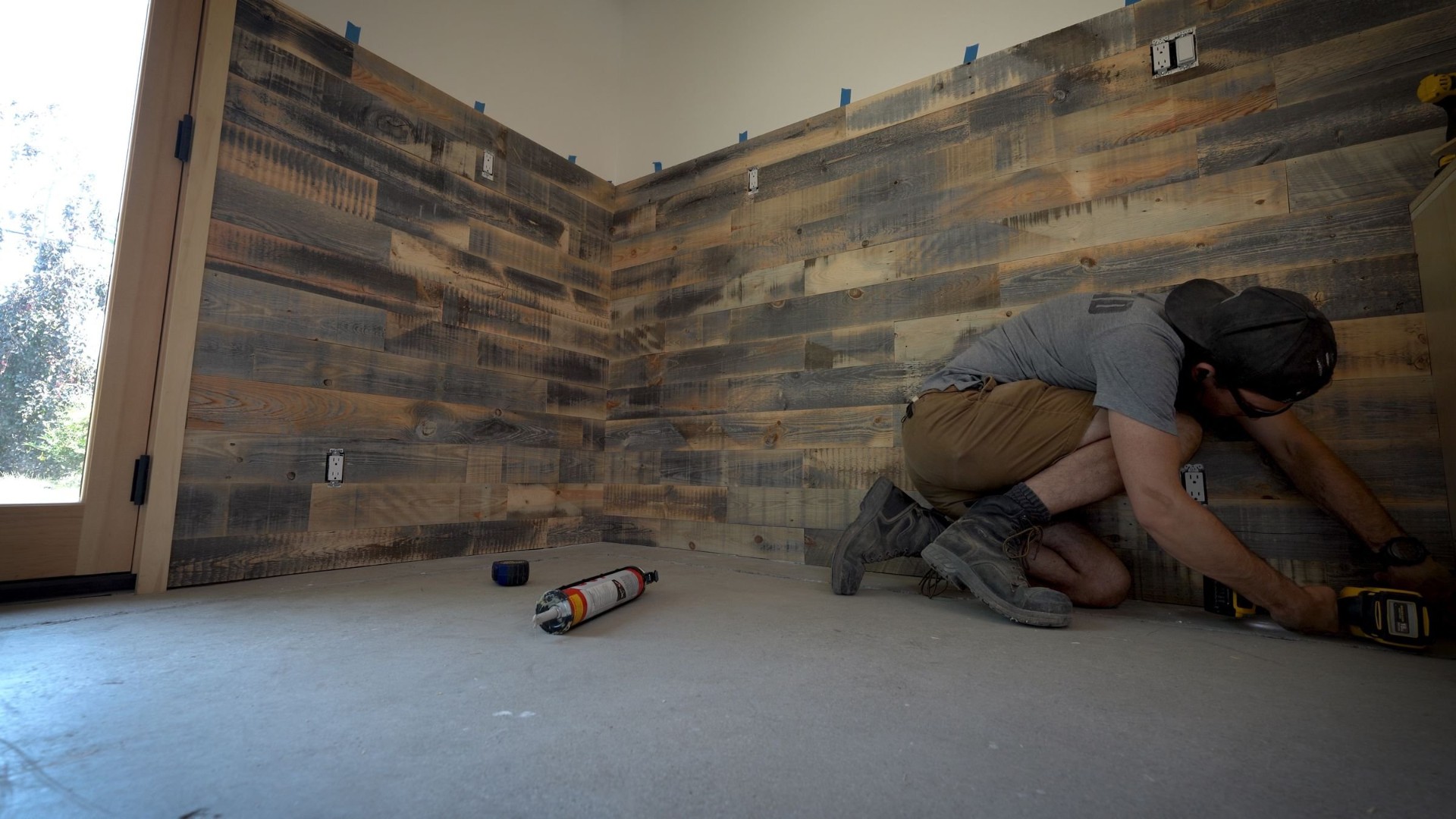 Reclaimed wood accent wall in a home workshop, mixed-tone boards with trim