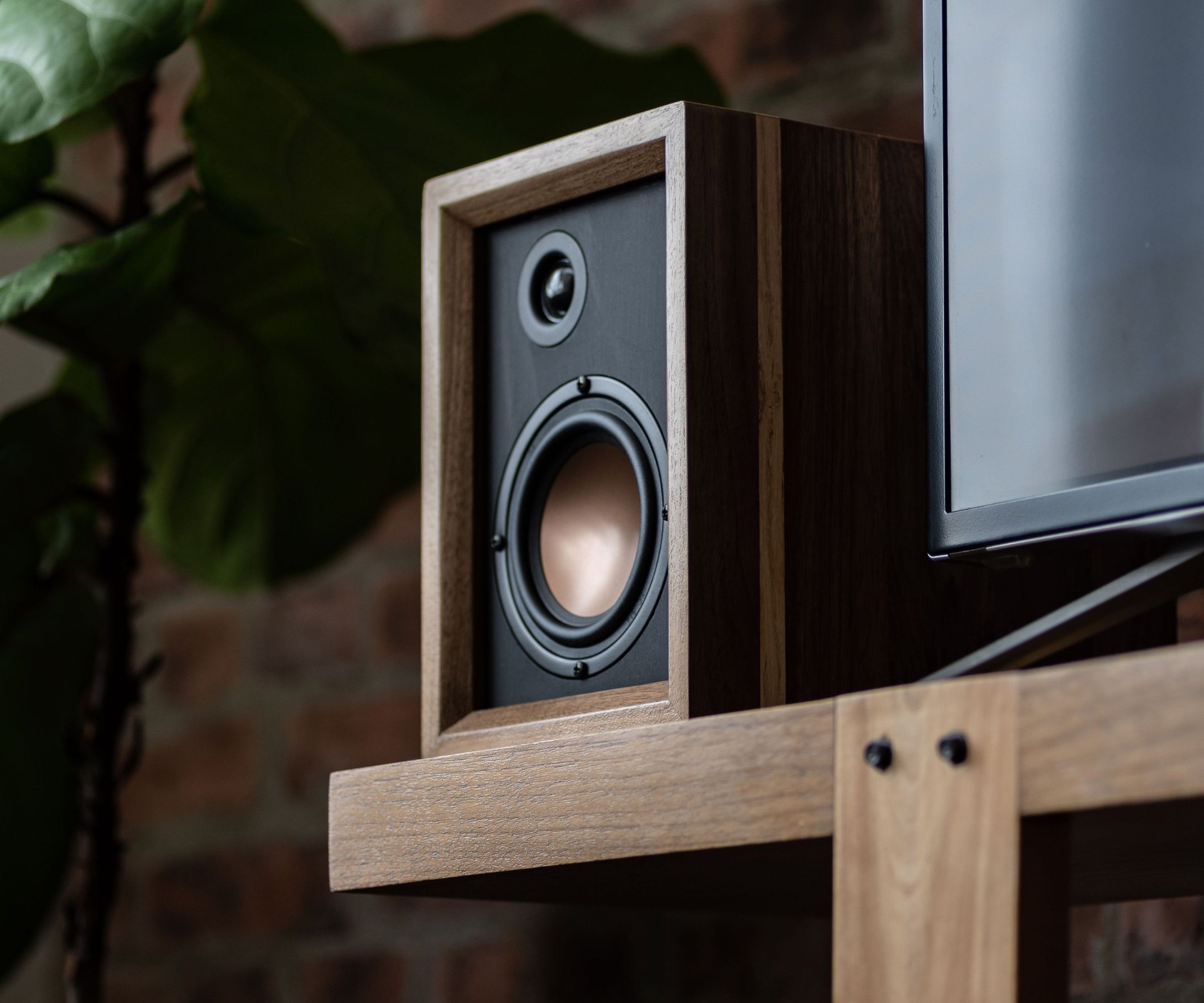 Pair of finished walnut speaker enclosures with copper accents on a shelf